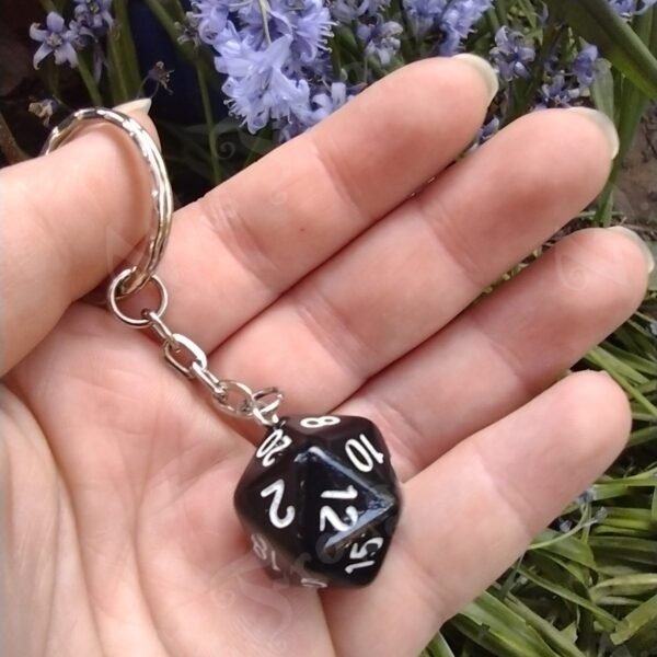 Black, 20-sided die on a silver-coloured metal keyring.